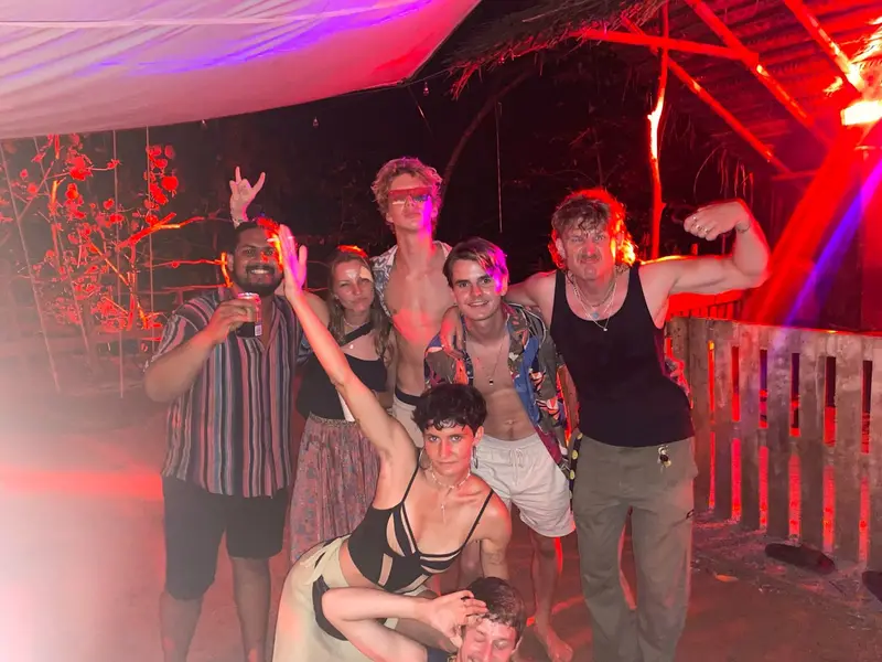 A group of guests posing and laughing under red lights on a night out