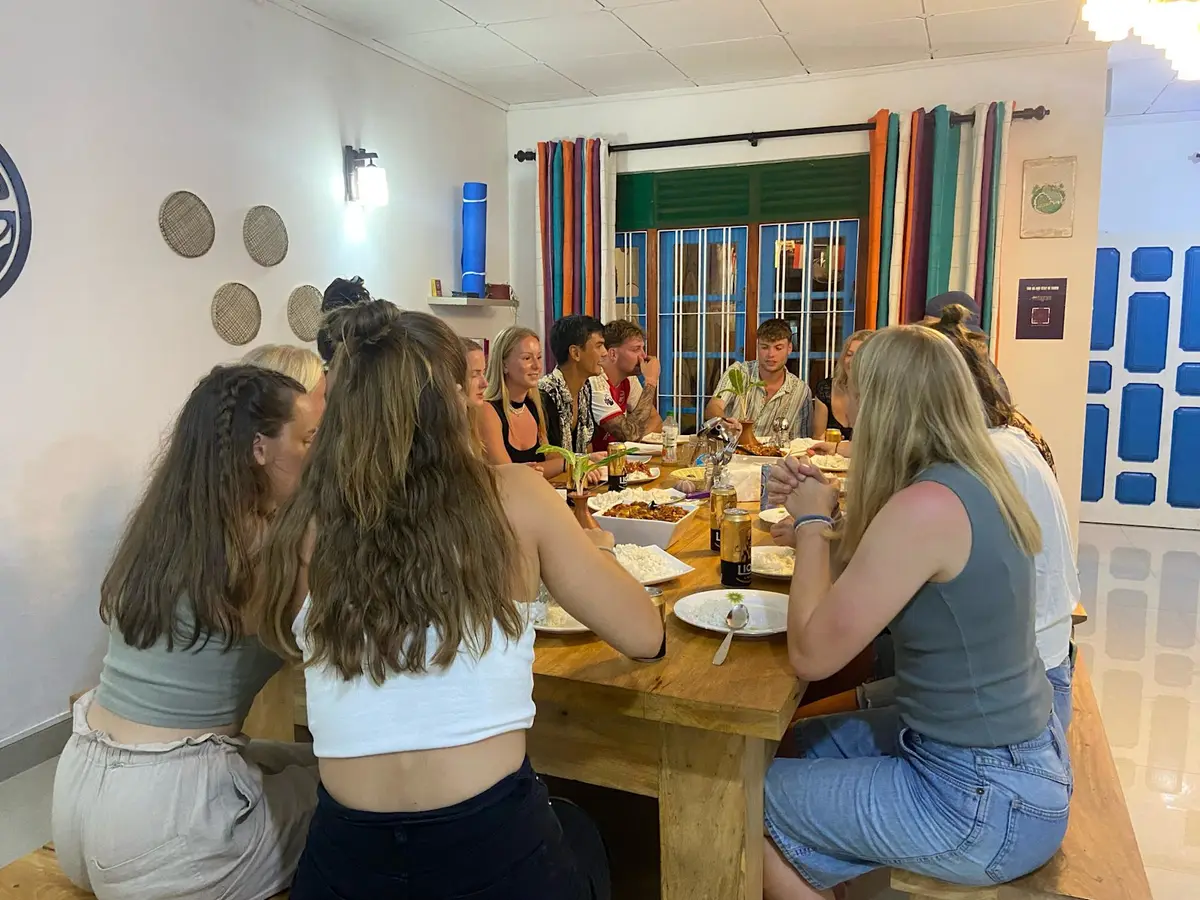 Guests chatting around the long wooden table at a Hiriketiya family dinner