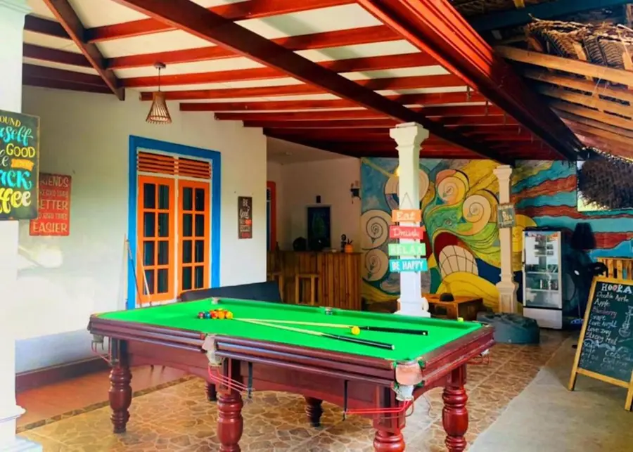 The Hiriketiya common room: a green pool table under a red-beamed roof, with a painted mural behind