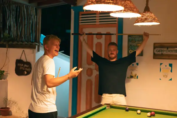 Two guests cheering over a game of pool