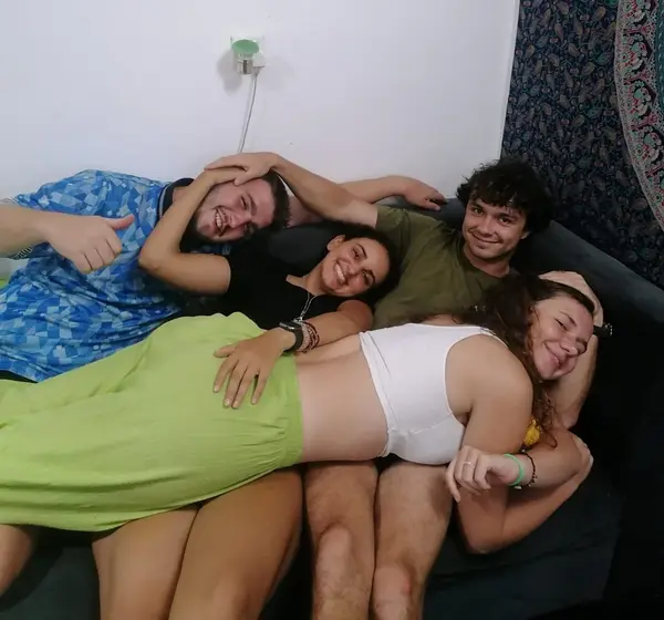 Four guests piled together laughing on a sofa