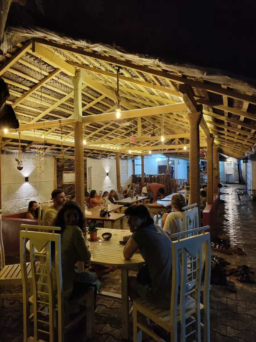Guests at tables under the thatched roof of the café in the evening
