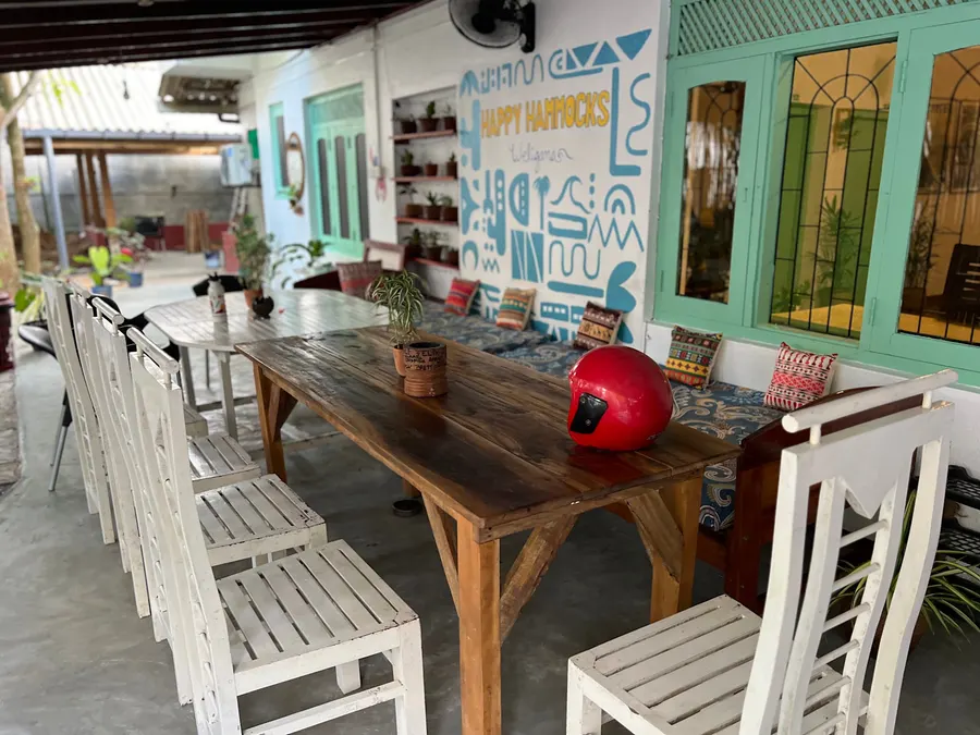 The long wooden dinner table on the Weligama veranda, beside a Happy Hammocks mural